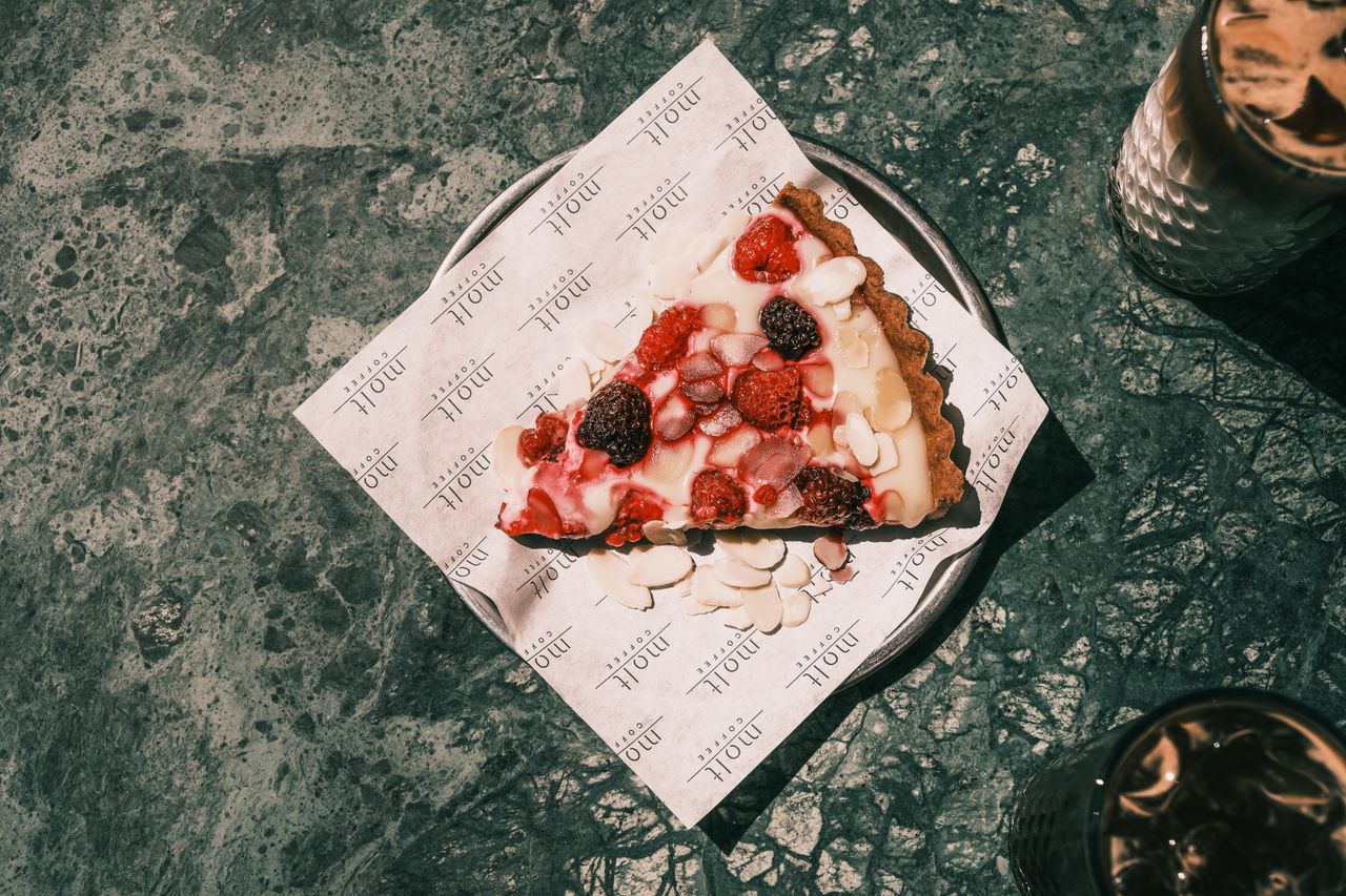 Top view of a delicious berry tart slice with cream on a plate, perfect for a dessert treat.